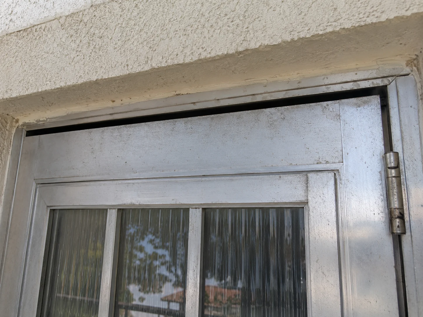 Before: corroded sliding door frame with gap and rust damage at top