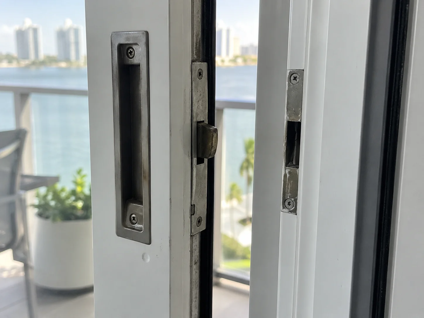 Old worn handle and latch assembly on sliding door being replaced for soundproofing
